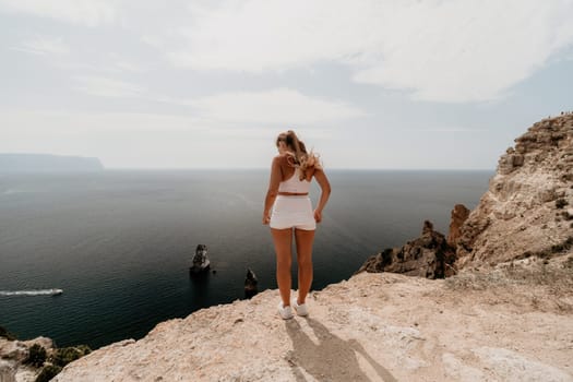 Woman travel sea. Happy tourist in hat enjoy taking picture outdoors for memories. Woman traveler posing on the beach at sea surrounded by volcanic mountains, sharing travel adventure journey