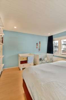 a bedroom with blue walls and wood flooring in the middle part of the room there is a white bed on the other side