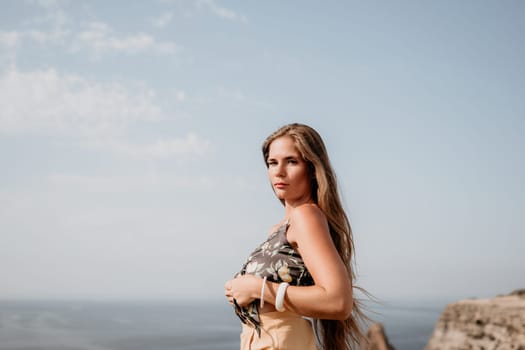 Woman travel sea. Happy tourist taking picture outdoors for memories. Woman traveler looks at the edge of the cliff on the sea bay of mountains, sharing travel adventure journey.