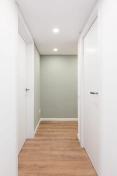Light corridor with entrances to rooms with doors and turning to the right. Concept of renovation and moving into a compact new apartment or mini hotel. Copyspace.