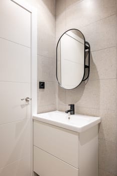 Mirror and cabinet for sink and faucet in a white small bathroom with beige tiles. Concept of a clean small cozy shower room. Bathroom in hotel.