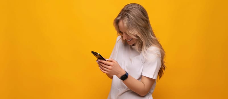 a woman with a smartphone in her hands chooses purchases on a yellow background.