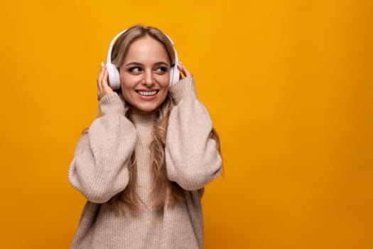 joyful european young woman enjoying meditation with headphones on yellow background.