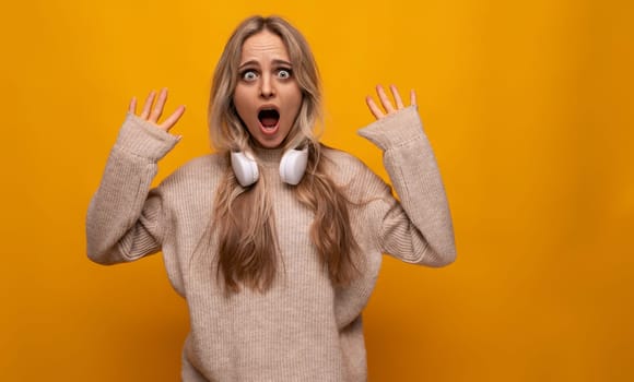 girl with a grimace in headphones on a yellow background.