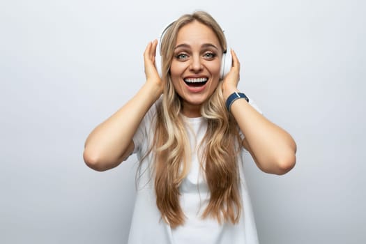 blond girl in headphones enjoys music on a white background.