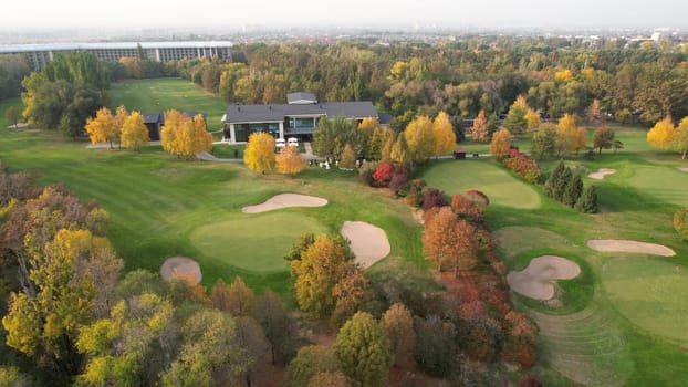 Beautiful house in a golf park. Autumn yellow-red trees. Top view from the drone on the green grass, fields, cafes with tents. A place for weddings, vacations and holidays. Yellow leaves. Sunset
