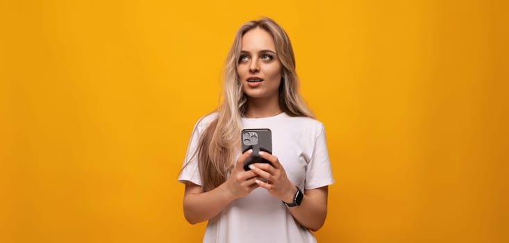 student girl with a phone in her hands on a yellow background.