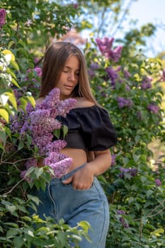 portrait of young woman with long hair outdoors in blooming lilac garden.