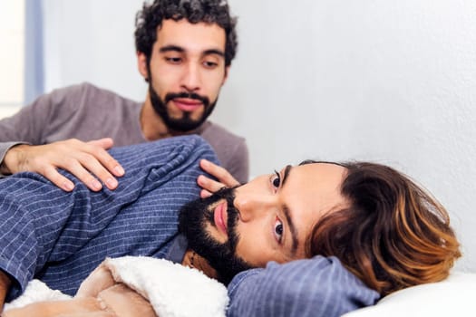 gay male couple together in bed when waking up in the morning, concept of real people lifestyle and love between people of the same sex