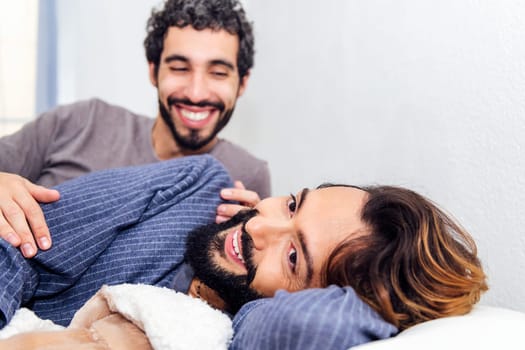 gay male couple relaxing together at bed and smiling happy in the morning, concept of real people lifestyle and love between people of the same sex