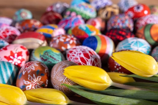 An aerial view of tightly stacked colorful Easter eggs and yellow tulips forming a distinctive composition for Easter Worlds.