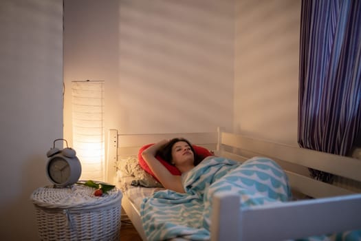 The girl sleeps on a large red pillow on her bed. A girl under a soft blanket.