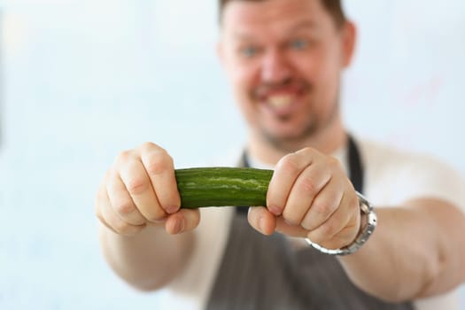 Emotional male cook with cucumber vegetable in hand. Cooking cucumbers in different dishes concept