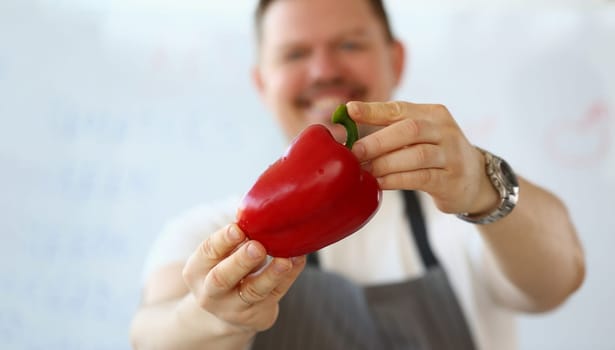 Smiling male cook holding red peppers. Culinary recipes and benefits of red pepper concept