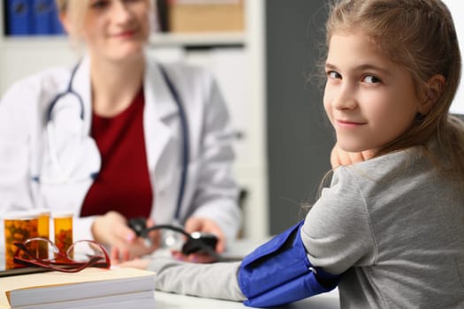 Doctor measures blood pressure of little girl child. Blood pressure in child norm and pathology concept