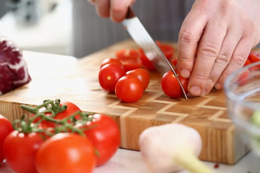 Chef cuts fresh ripe tomatoes on cutting board. Cooking vegetable salad and the benefits of tomatoes concept