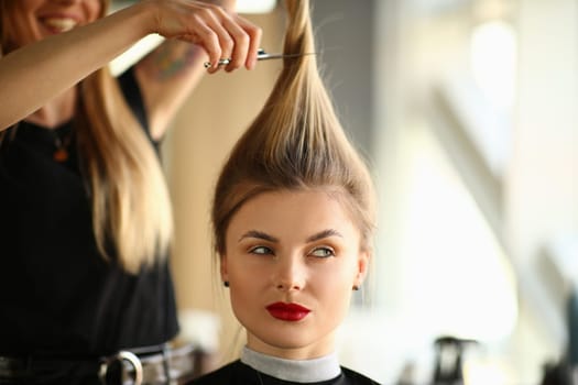 Woman hairdresser cuts long hair to client in beauty salon. Fashionable haircuts for long hair concept
