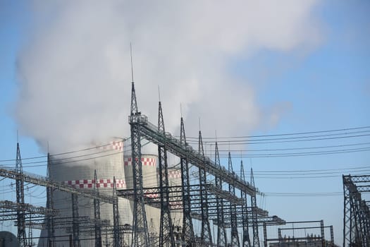 Smoking chimneys of various sizes of thermal power plant against blue sky. Thermal power plant concept