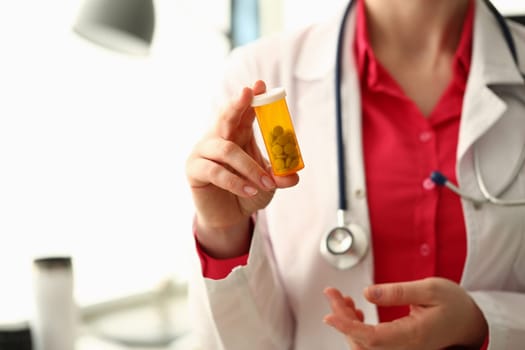 Closeup of doctor holding container of medical pills. Health care medicine and treatment concept