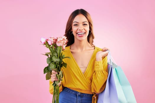 Happy, shopping bags and flowers with portrait of woman in studio for retail, birthday and spring. Event, party and smile with female and roses on pink background for sale, discount and romance.