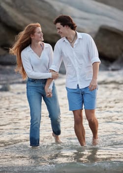 Couple walking in ocean, holding hands and travel with love and commitment in relationship with adventure at beach. Trust, partnership and care with people outdoor, romance and happiness together.