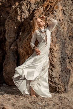 Middle aged woman looks good with blond hair, boho style in white long dress on the beach decorations on her neck and arms