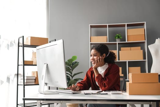 sme business idea. African Americans woman selling online at home with laptop to take orders and to deliver yellow parcel boxes online delivery ideas.