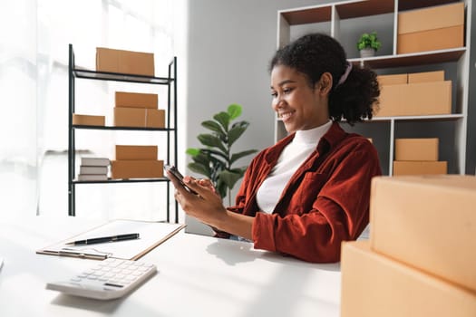 sme business idea. African Americans woman selling online at home with laptop to take orders and to deliver yellow parcel boxes online delivery ideas.