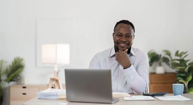 Professional male economist searches needed information on portable computer, happy to recieve high net profit, spends important banking operation. Black male trader analyzes financial market..