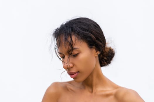 Beauty portrait of young topless african american woman with bare shoulders on white background with perfect skin and natural makeup positive