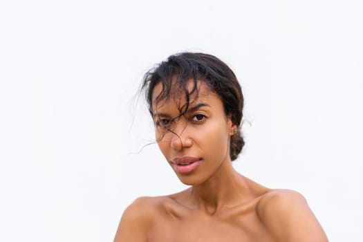 Beauty portrait of young topless african american woman with bare shoulders on white background with perfect skin and natural makeup positive