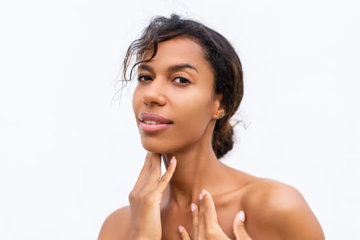 Beauty portrait of young topless african american woman with bare shoulders on white background with perfect skin and natural makeup positive