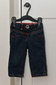 A baby trousers hang on a hanger