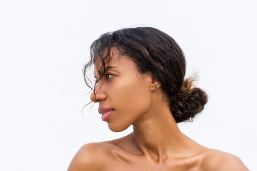 Beauty portrait of young topless african american woman with bare shoulders on white background with perfect skin and natural makeup positive