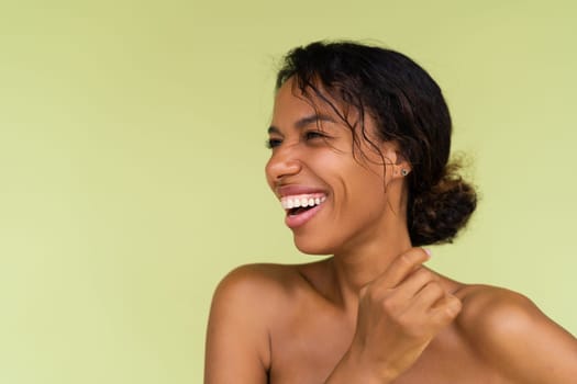 Beauty portrait of young topless african american woman with bare shoulders on green background with perfect skin and natural makeup