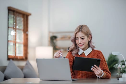 Young asian woman using tablet with smiling face, positive emotion, at home, casual home life concept..