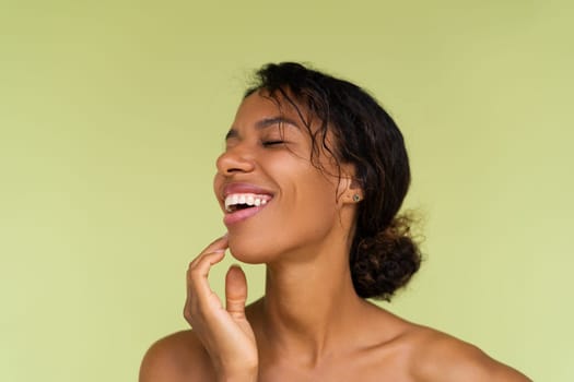 Beauty portrait of young topless african american woman with bare shoulders on green background with perfect skin and natural makeup