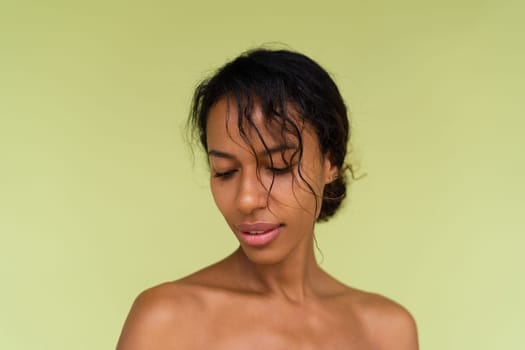 Beauty portrait of young topless african american woman with bare shoulders on green background with perfect skin and natural makeup