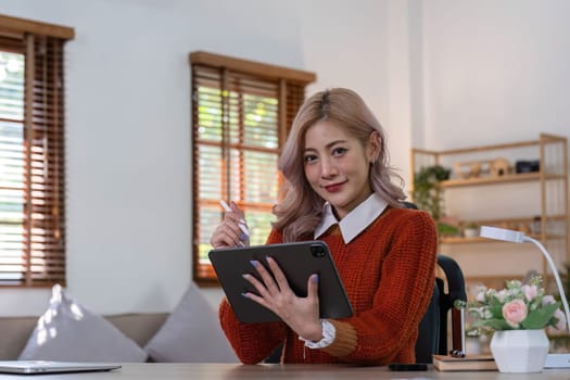 Young asian woman using tablet with smiling face, positive emotion, at home, casual home life concept..