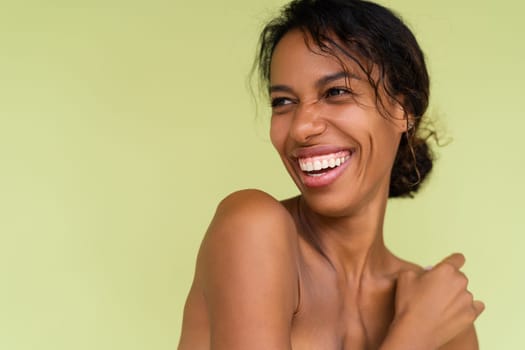 Beauty portrait of young topless african american woman with bare shoulders on green background with perfect skin and natural makeup