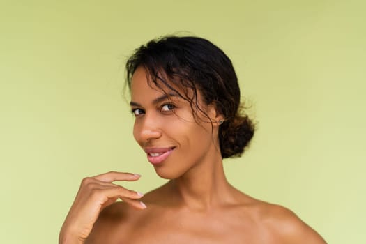 Beauty portrait of young topless african american woman with bare shoulders on green background with perfect skin and natural makeup