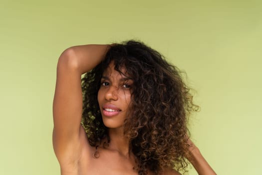 Beauty portrait of young topless african american woman with bare shoulders on green background with perfect skin and natural makeup