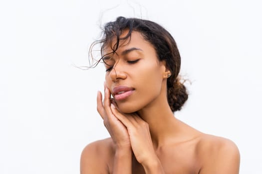 Beauty portrait of young topless african american woman with bare shoulders on white background with perfect skin and natural makeup positive