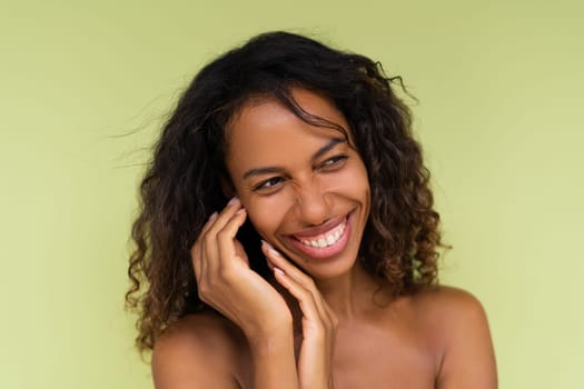 Beauty portrait of young topless african american woman with bare shoulders on green background with perfect skin and natural makeup