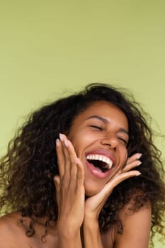 Beauty portrait of young topless african american woman with bare shoulders on green background with perfect skin and natural makeup