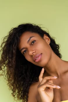 Beauty portrait of young topless african american woman with bare shoulders on green background with perfect skin and natural makeup