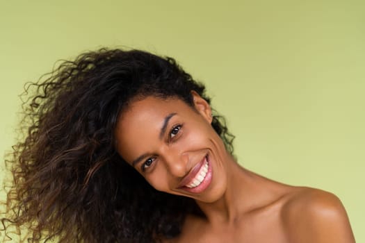 Beauty portrait of young topless african american woman with bare shoulders on green background with perfect skin and natural makeup