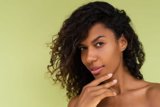 Beauty portrait of young topless african american woman with bare shoulders on green background with perfect skin and natural makeup