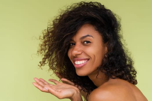Beauty portrait of young topless african american woman with bare shoulders on green background with perfect skin and natural makeup