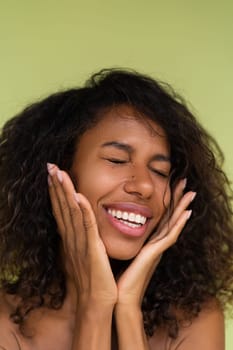 Beauty portrait of young topless african american woman with bare shoulders on green background with perfect skin and natural makeup